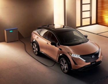 Nissan ARIYA plugged-in and charging outside a home | Nissan of Pittsfield in Pittsfield MA